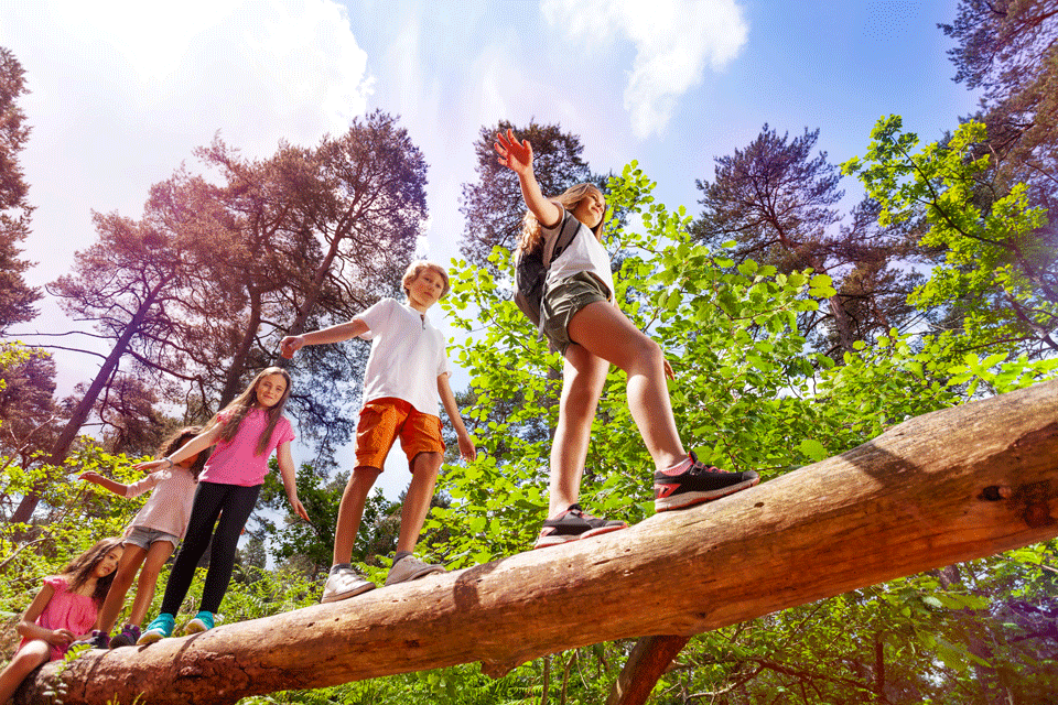 Kids walking on a log during camp.