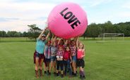Kids and counselor hold a 'love' balloon pose. 